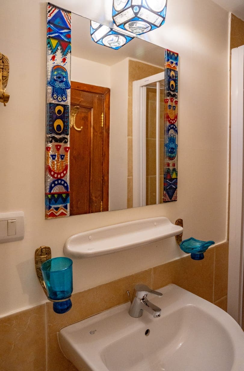 Stained glass mirror and artisanal glass bathroom fixtures